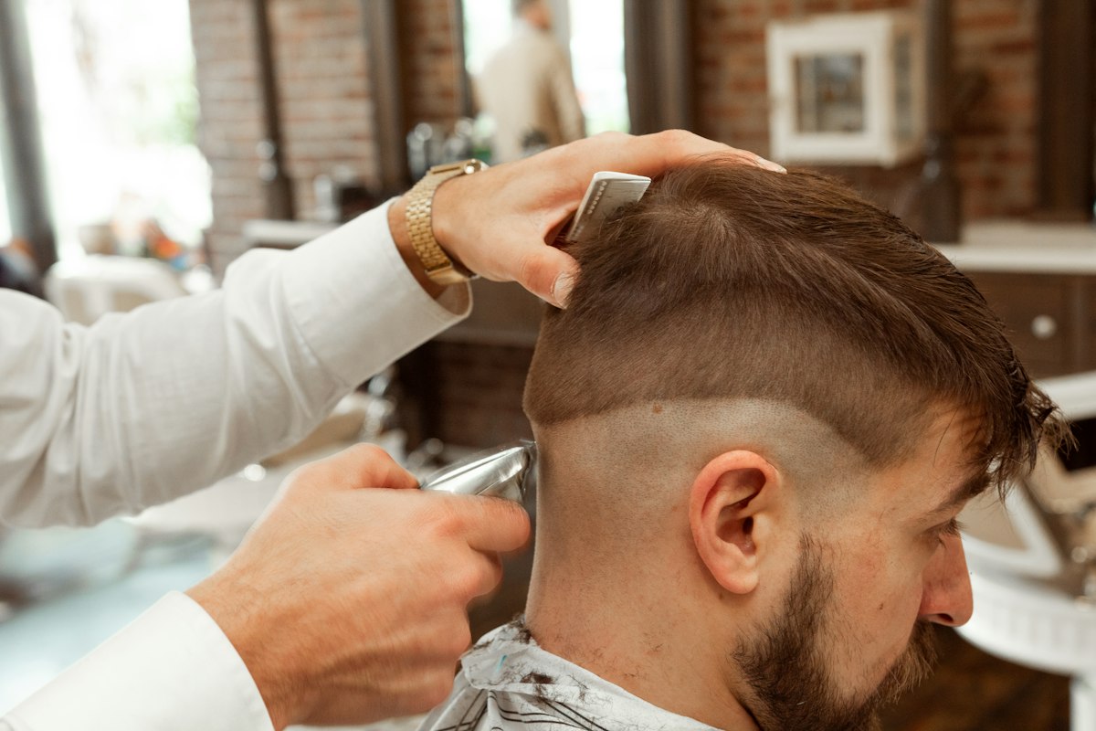 Barbero realizando un corte de cabello a un cliente, foto de referencia